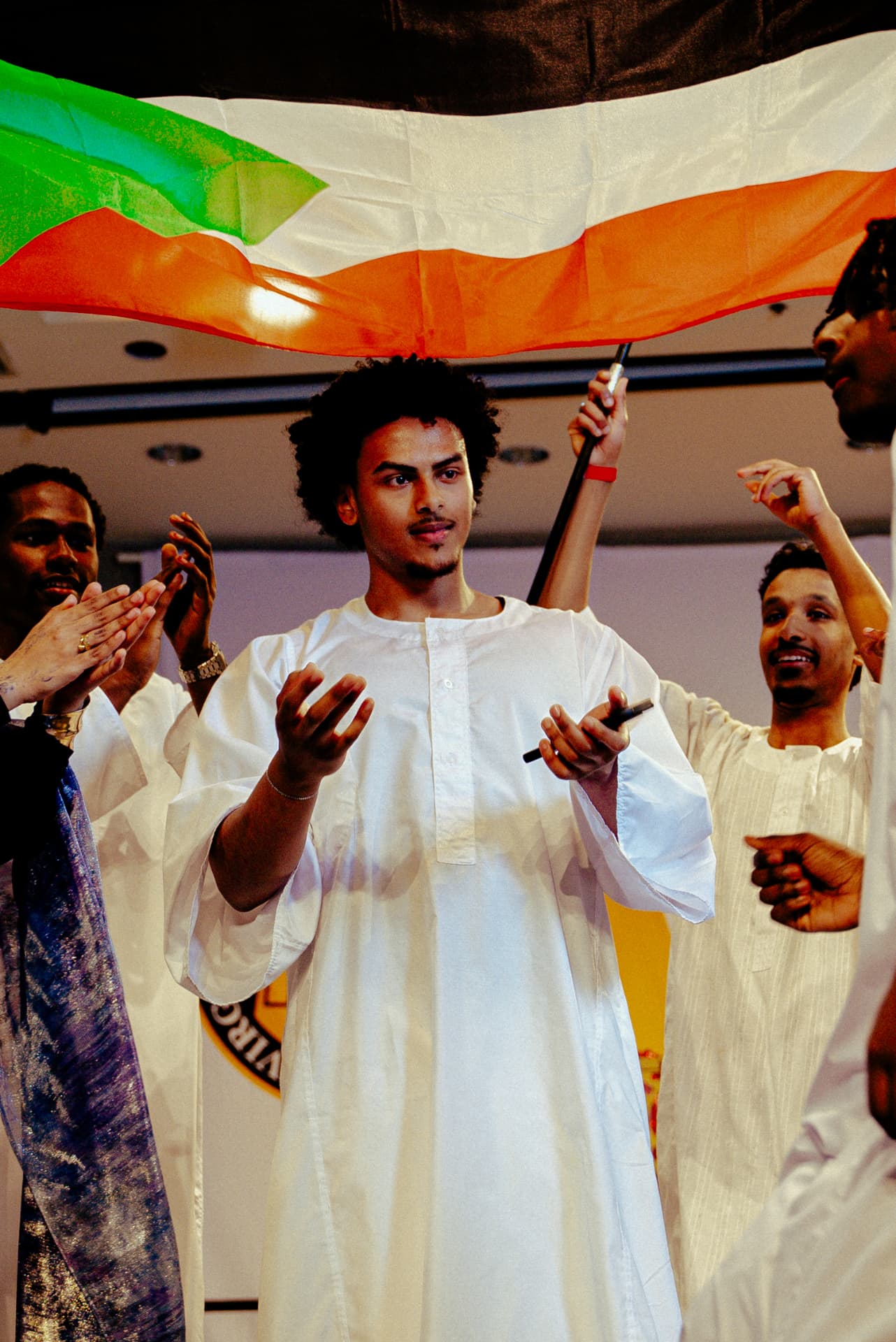 Student performing under a Sudanese flag while others clap